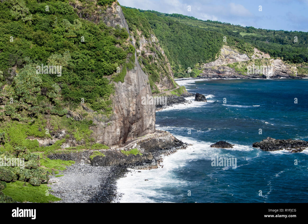 Maui Cliff Road: una stretta strada curva attorno ad una roccia come l'autostrada Piiliani costeggia il litorale orientale di Maui. Foto Stock