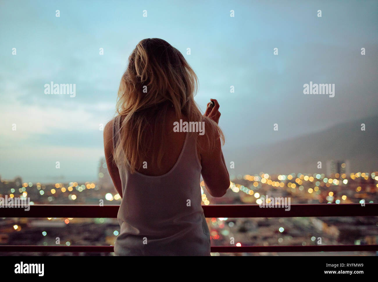 Vista posteriore del disheveled donna che guarda la vista. Spegnimento / spegnimento dopo una dura giornata. Stile di vita / vita di città / mindfulness concetto. Maggio 2018 Foto Stock