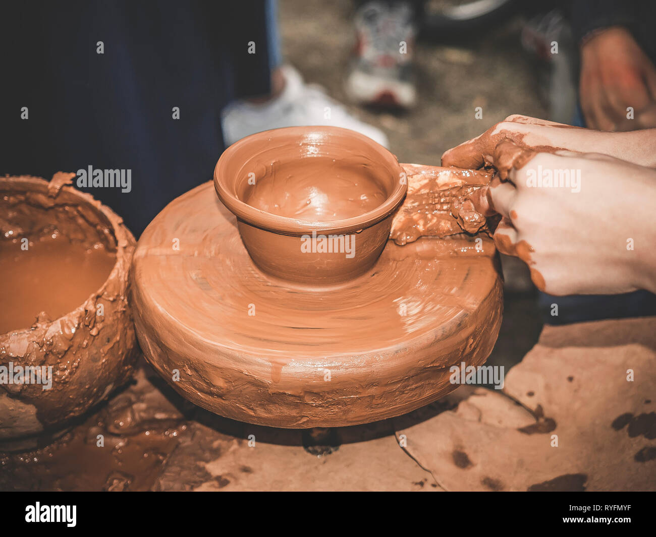 Ruotare tornio del vasaio e argilla ware su di essa presa da sopra. Un fanciullo scolpisce le sue mani con un bicchiere di argilla su un tornio del vasaio. Mani in argilla. In ceramica Foto Stock