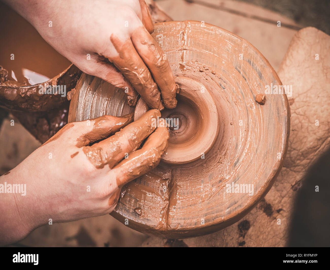 Ruotare tornio del vasaio e argilla ware su di essa presa da sopra. Un scolpisce le sue mani con un bicchiere di argilla su un tornio del vasaio. Mani in argilla. Maschio in ceramica Foto Stock