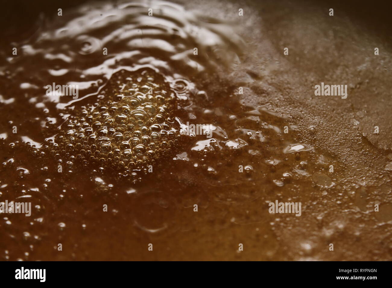In ebollizione il liquido viscoso di colore arancione e bolle. Foto Stock