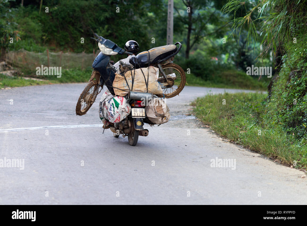 Uomo che porta uno scooter su una moto di Sapa. Popolo vietnamita sono  utilizzati per il carico e il trasporto di un sacco di cose sul motociclo.  Il Vietnam Foto stock -