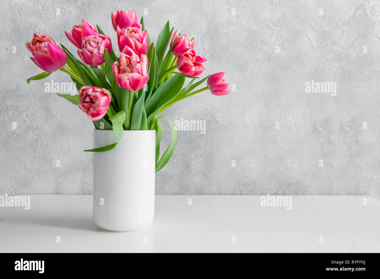 Bouquet di tulipani rossi in vaso su bianco tavola vintage. Spazio per il testo. Foto Stock