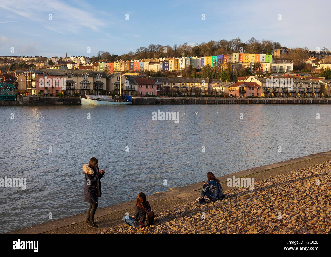 Le tre ragazze sui loro telefoni cellulari sulle rive del Floating Harbour, Bristol Foto Stock