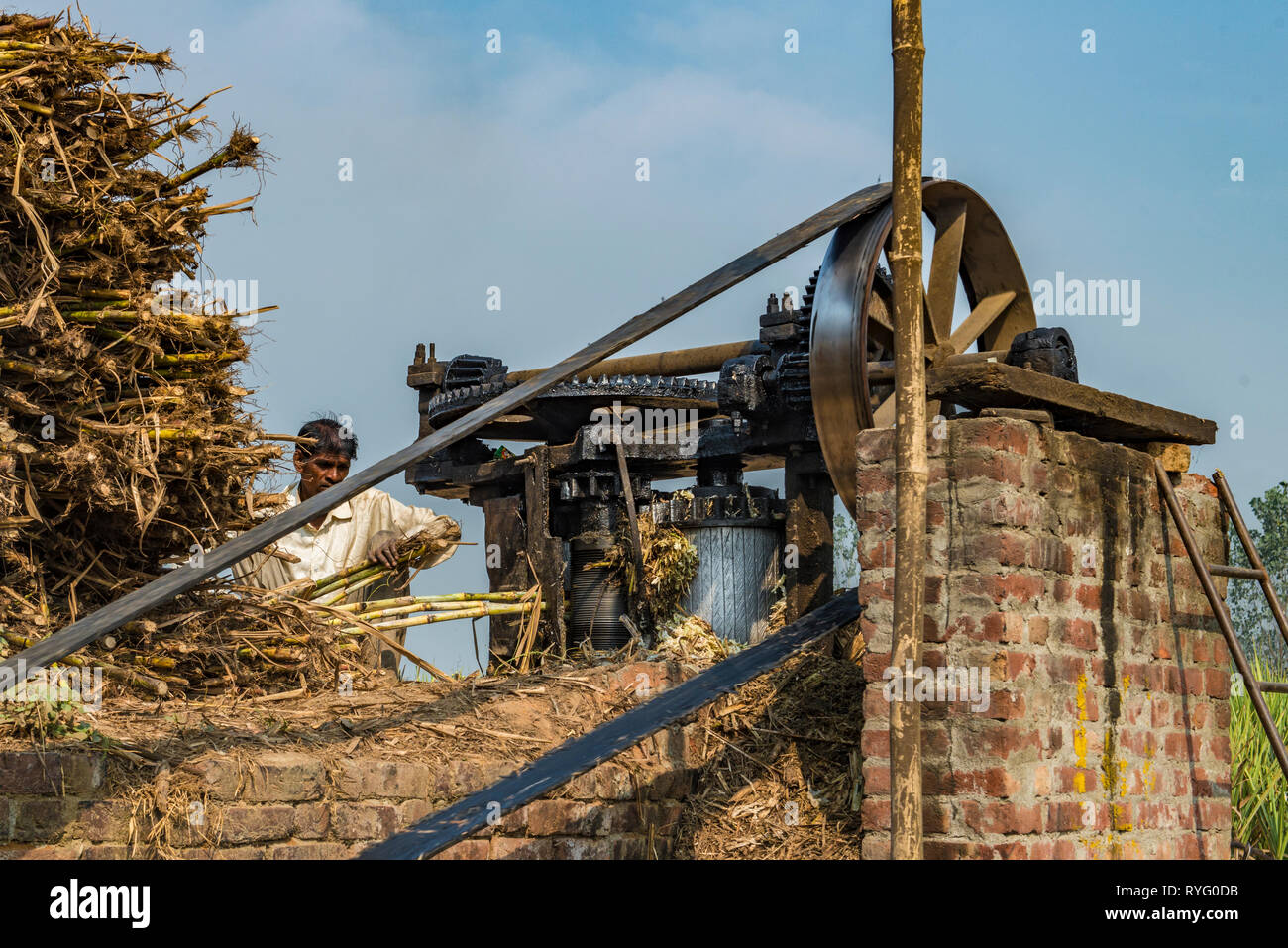 HIMACHAL Pradesh, India,lavoratore funzionamento di una macchina di spremitura per la canna da zucchero in India rurale Foto Stock