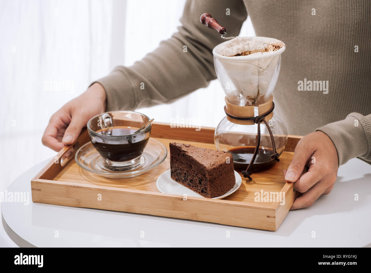 Caffè di gocciolamento sul vassoio in legno con torta al cioccolato. Tempo di caffè sul cafe con luce naturale Foto Stock