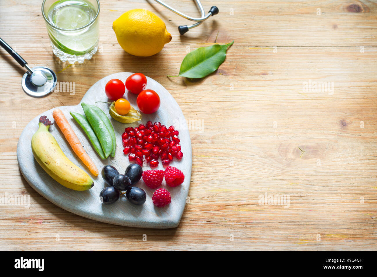 Uno stile di vita sano cibo vegetariano nel cuore e lo stetoscopio con acqua medicina alternativa il concetto di sfondo Foto Stock