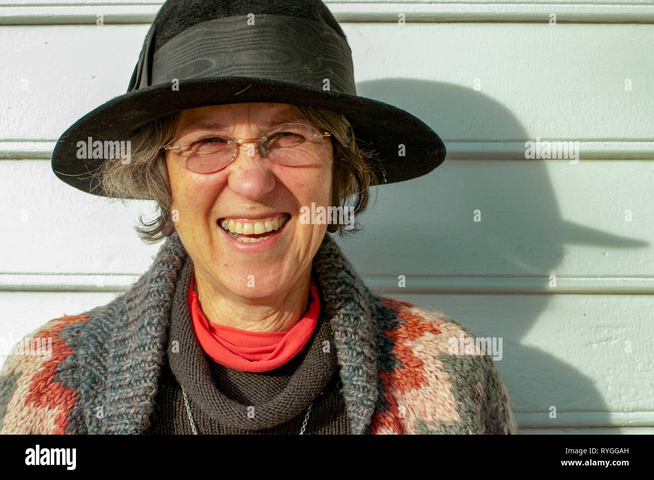 Ritratto di una donna matura in un cappello nero e bicchieri pieni di risate e di gioia Foto Stock