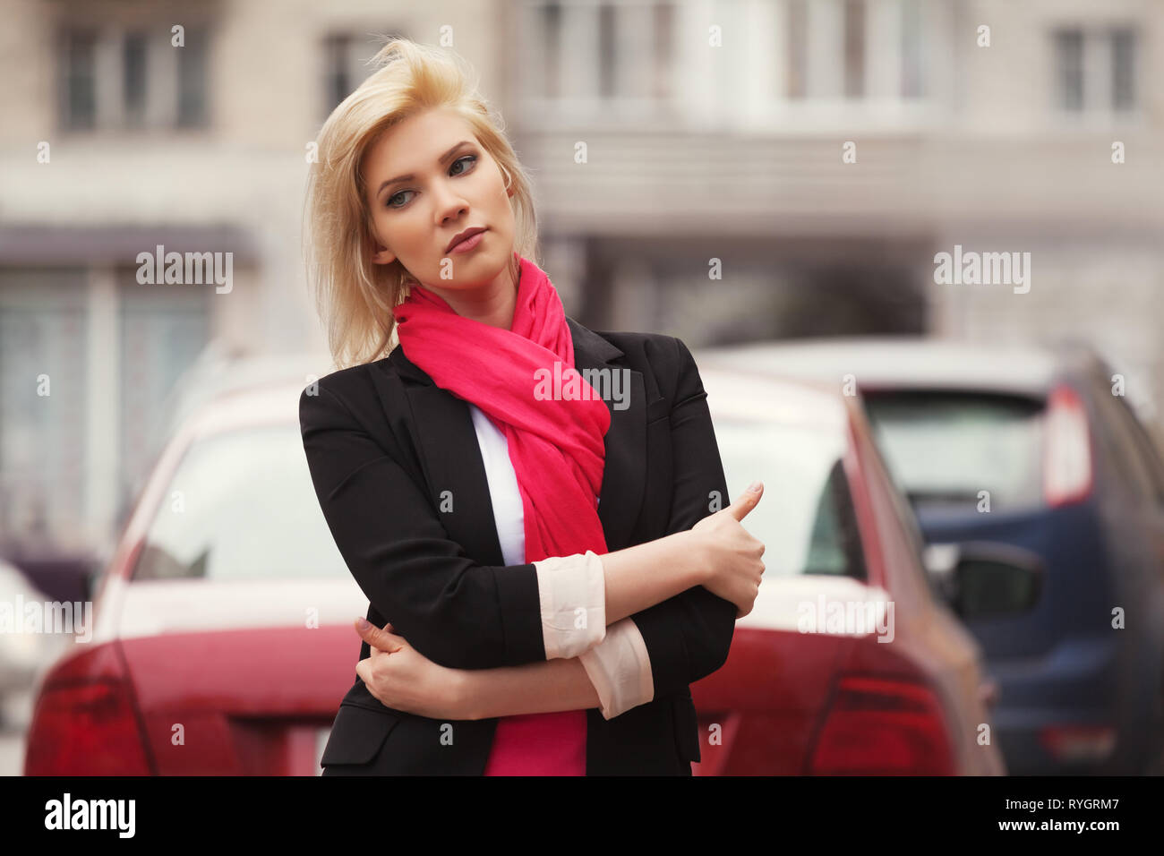 Moda giovane donna di affari a piedi nella città strada elegante modello femminile indossando abito nero giacca e sciarpa rossa all'aperto Foto Stock