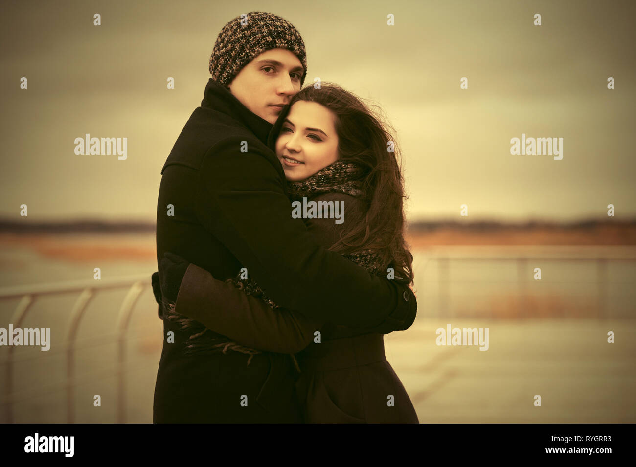 Felice coppia giovane in amore abbracciando outdoor elegante l uomo e la donna nel classico cappotti beanie e sciarpa Foto Stock