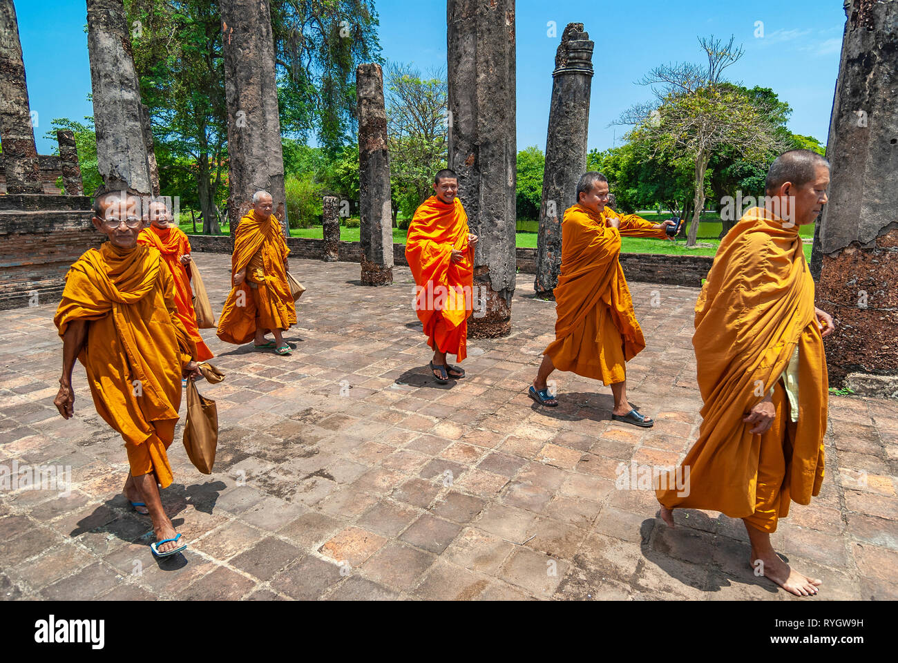 Un gruppo di monaci buddisti a piedi e sorridente durante una visita in uno dei templi del buddismo e rovine di Sukhothai, Thailandia, in Asia. Foto Stock