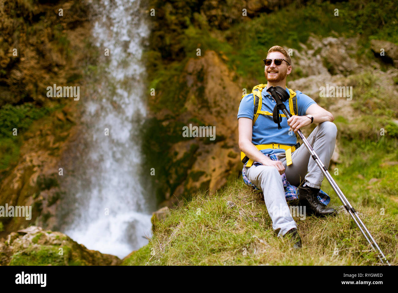 Bel giovane capelli rossi escursionista fermato accanto a una cascata di montagna a riposo Foto Stock