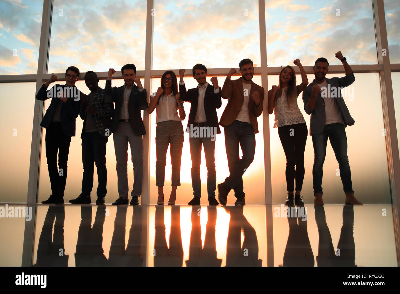 Un gruppo di giovani professionisti in piedi in un ufficio con una grande finestra Foto Stock