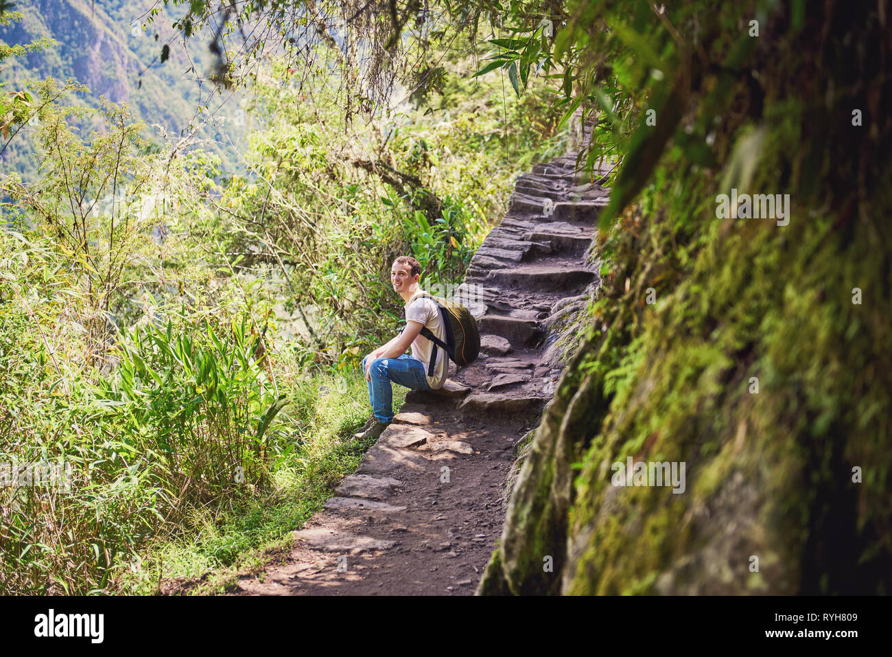 Uomo seduto su pietra escursionismo strada sulla luminosa giornata di sole Foto Stock