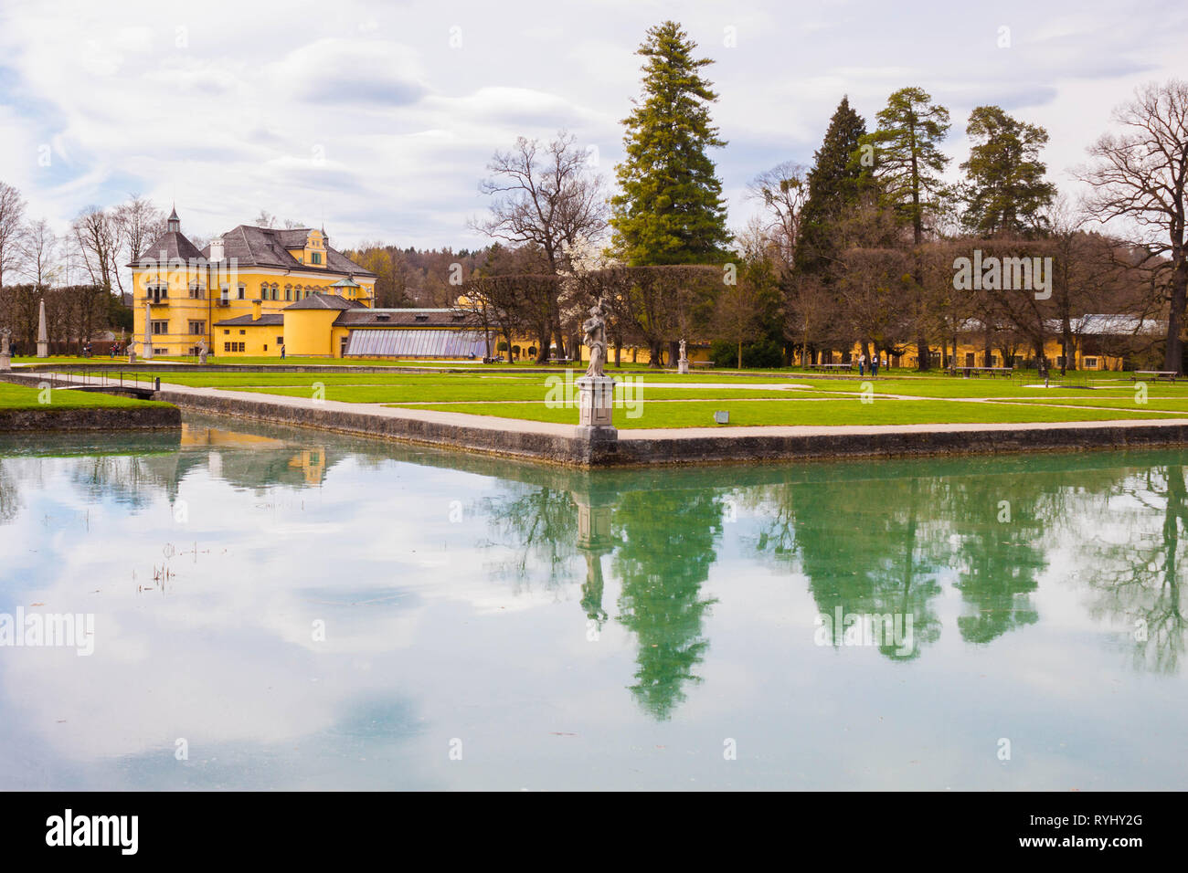 Il castello di Hellbrunn (Schloss Hellbrunn) e del parco in una bella giornata di primavera. Sculture e alberi che riflettono nelle acque della piscina. Salisburgo, Austria. Foto Stock