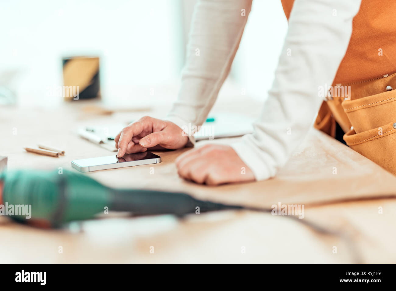 Falegname femmina è utilizzando il telefono cellulare per la messaggistica di testo da vicino delle mani la digitazione di SMS sullo smartphone touchscreen, il fuoco selettivo Foto Stock