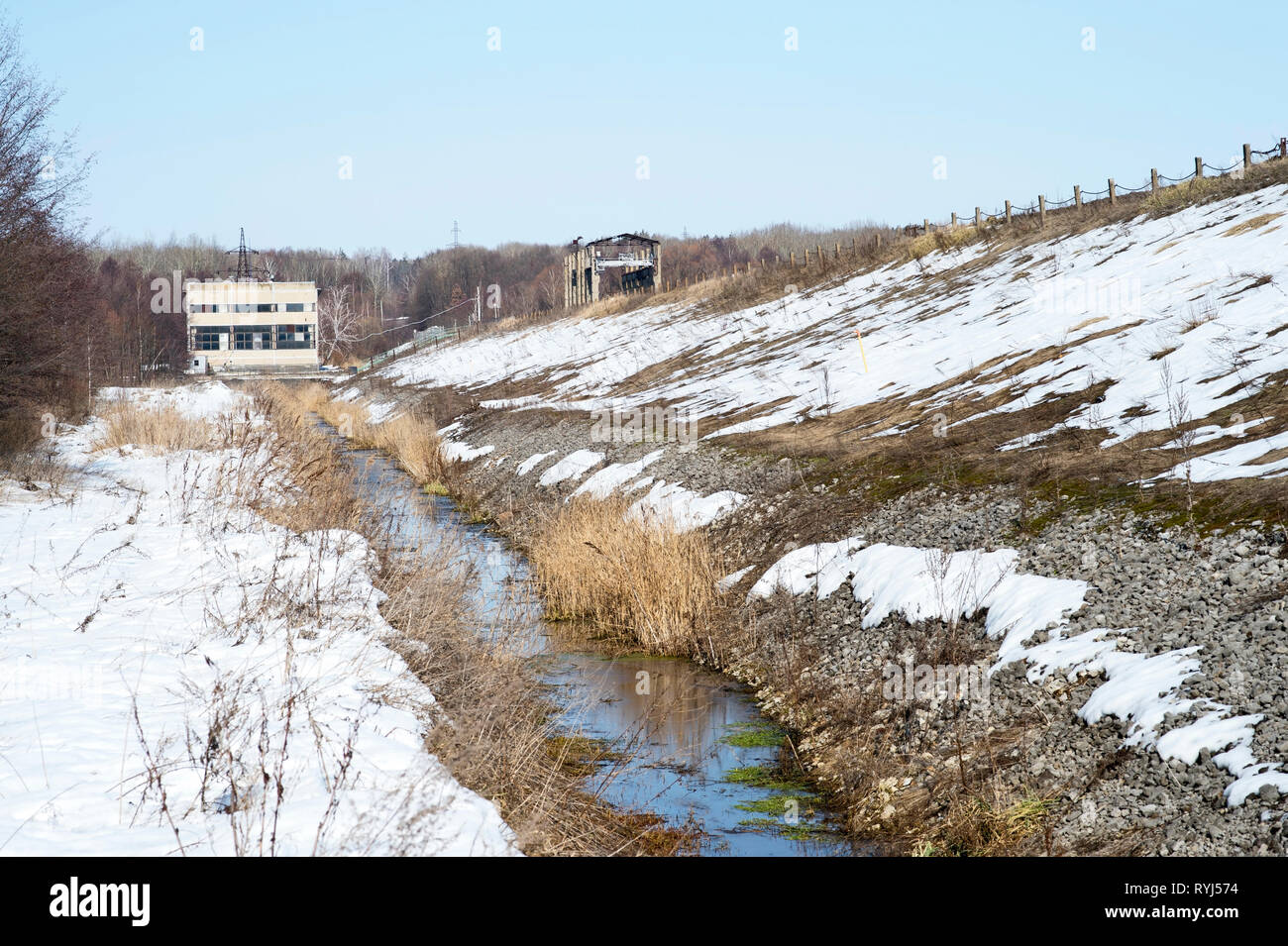 Il dispositivo della diga di un serbatoio di grandi dimensioni con una stazione di pompaggio di un sistema di chiuse nella parte superiore e di un canale di drenaggio. Paesaggio industriale in primavera Foto Stock