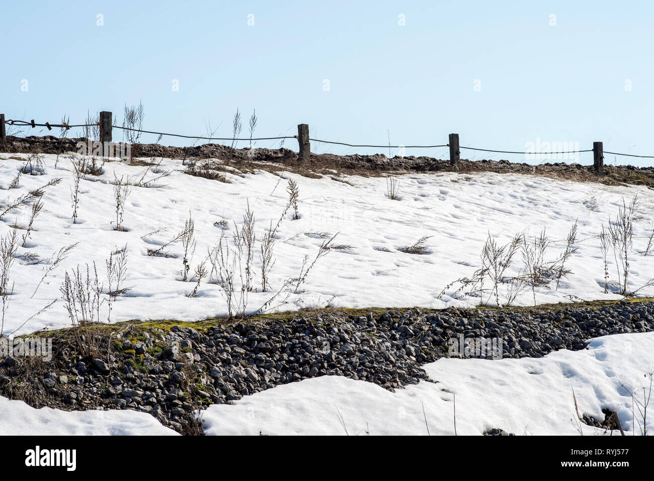 Il dispositivo della diga in forma di un terrapieno fortificato di ghiaia grigia con una strada sulla parte superiore. Vista dal basso. Foto Stock