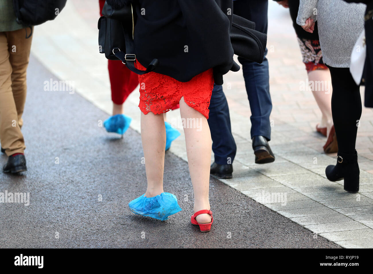 Un racegoer indossando un pattino di plastica coperchio durante il St Patrick giovedì del 2019 Cheltenham Festival a Cheltenham Racecourse. Foto Stock