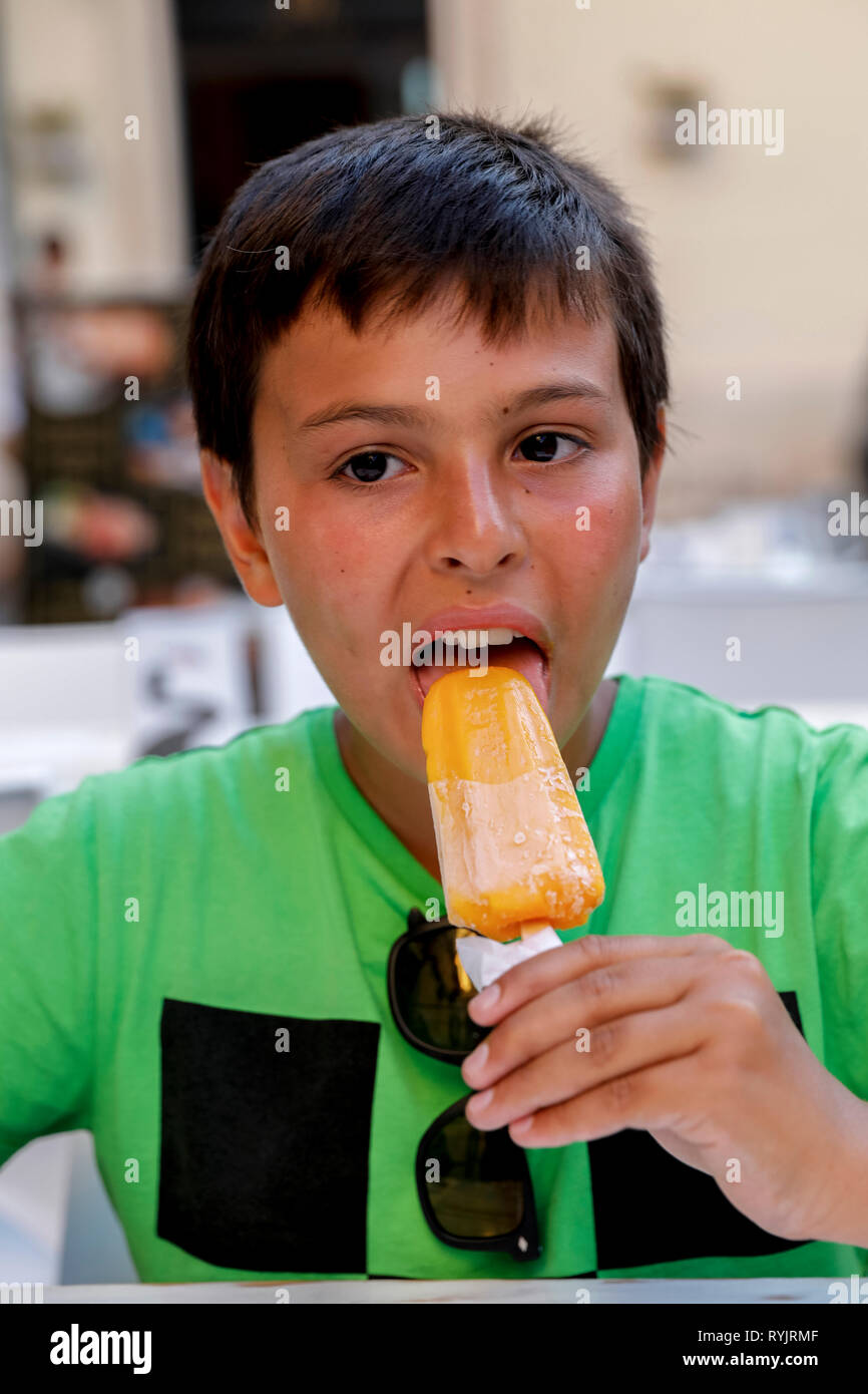 12-anno-vecchio ragazzo di mangiare un gelato a Siracusa, in Sicilia (Italia). Foto Stock