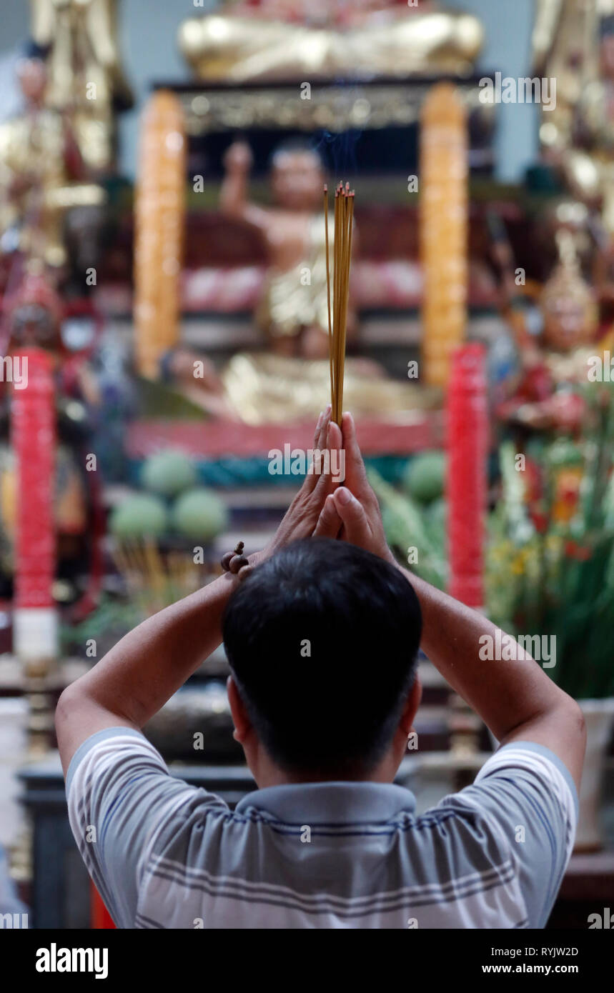 Uomo che prega il Buddha. Bastoncini di incenso. Tay un tempio. Chau Doc. Il Vietnam. Foto Stock