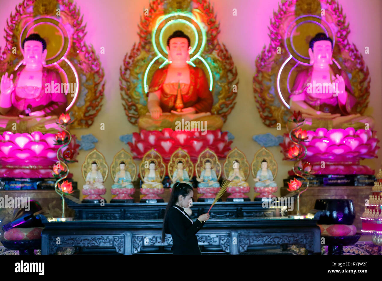 Huynh Dao pagoda buddista. Donna che prega il Buddha. Bastoncini di incenso. Statue di Buddha sull altare principale. Chau Doc. Il Vietnam. Foto Stock