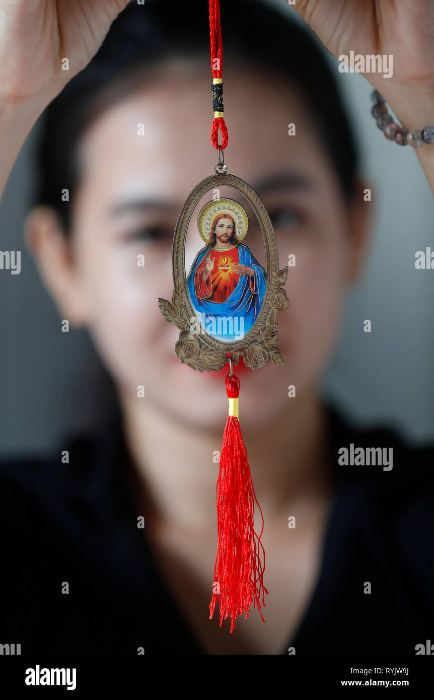Donna e un Gesù Sacro Cuore medaillon. Ho Chi Minh City. Il Vietnam. Foto Stock