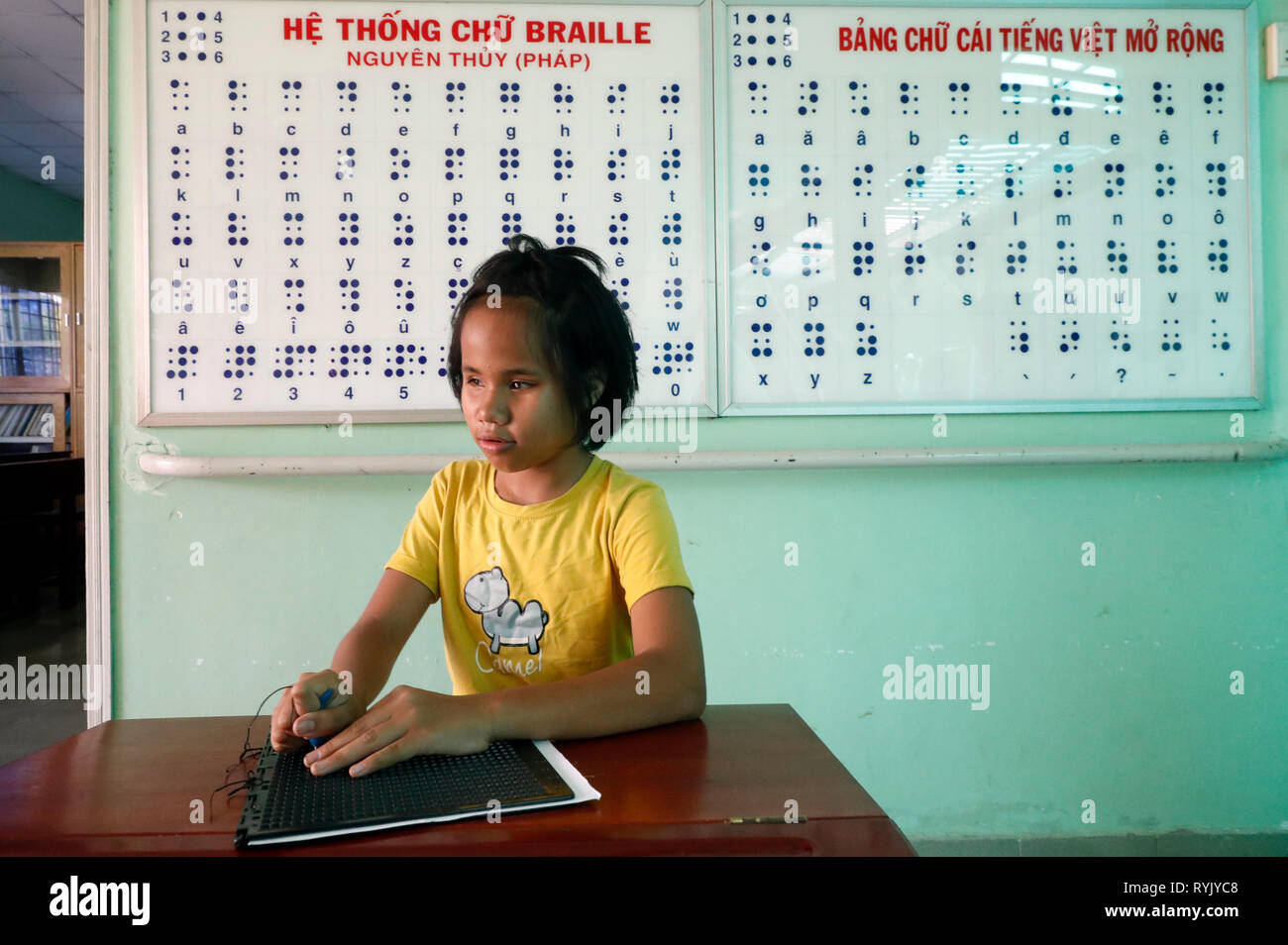 Centro per i bambini ciechi gestito da bambini azione. Ragazza scrittura braille. Ho Chi Minh city. Il Vietnam. Foto Stock