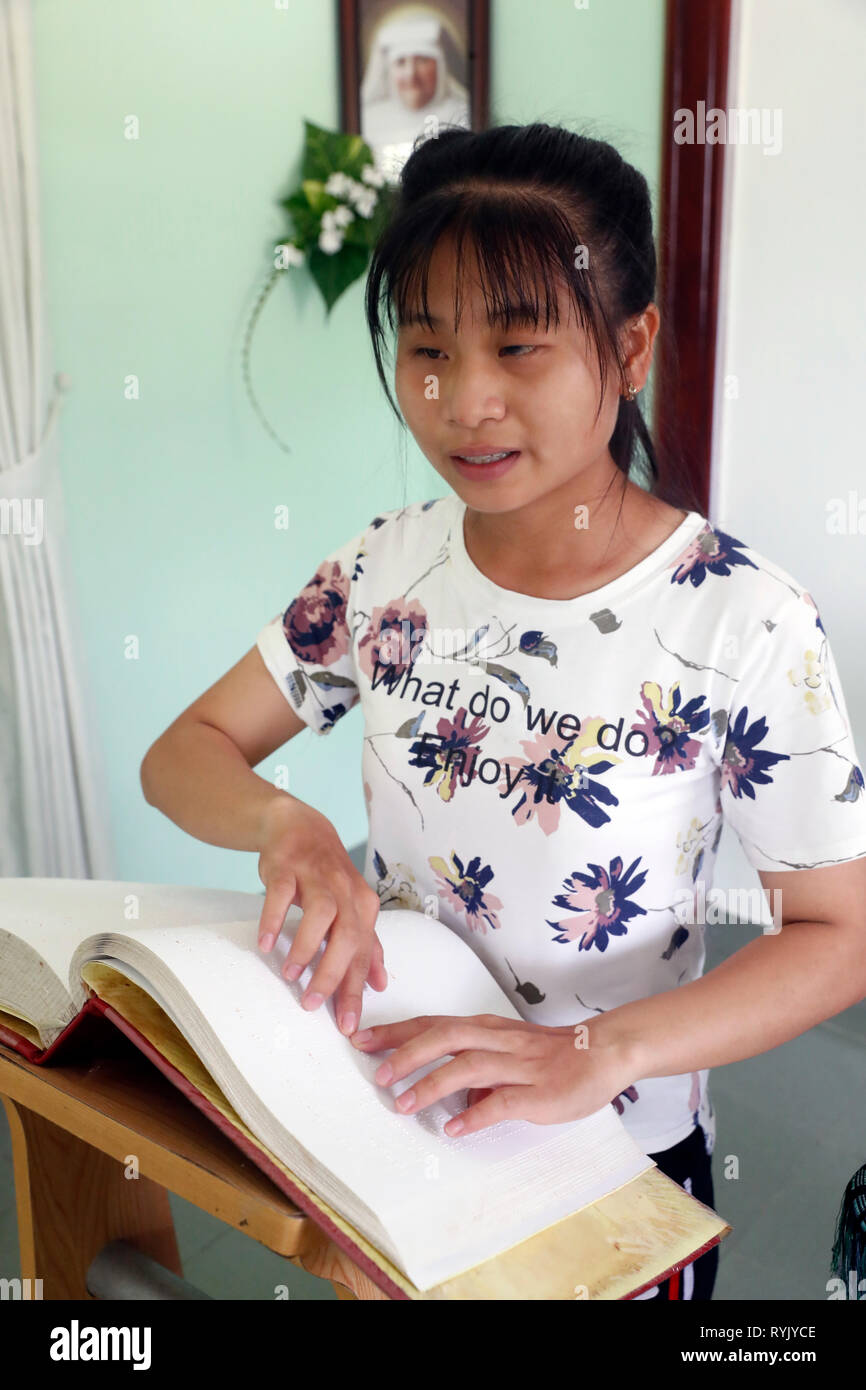 Centro per i bambini ciechi gestito da bambini azione. La cappella cattolica. Ragazza cieca la lettura di una versione braille della Bibbia. Ho Chi Minh city. Il Vietnam. Foto Stock