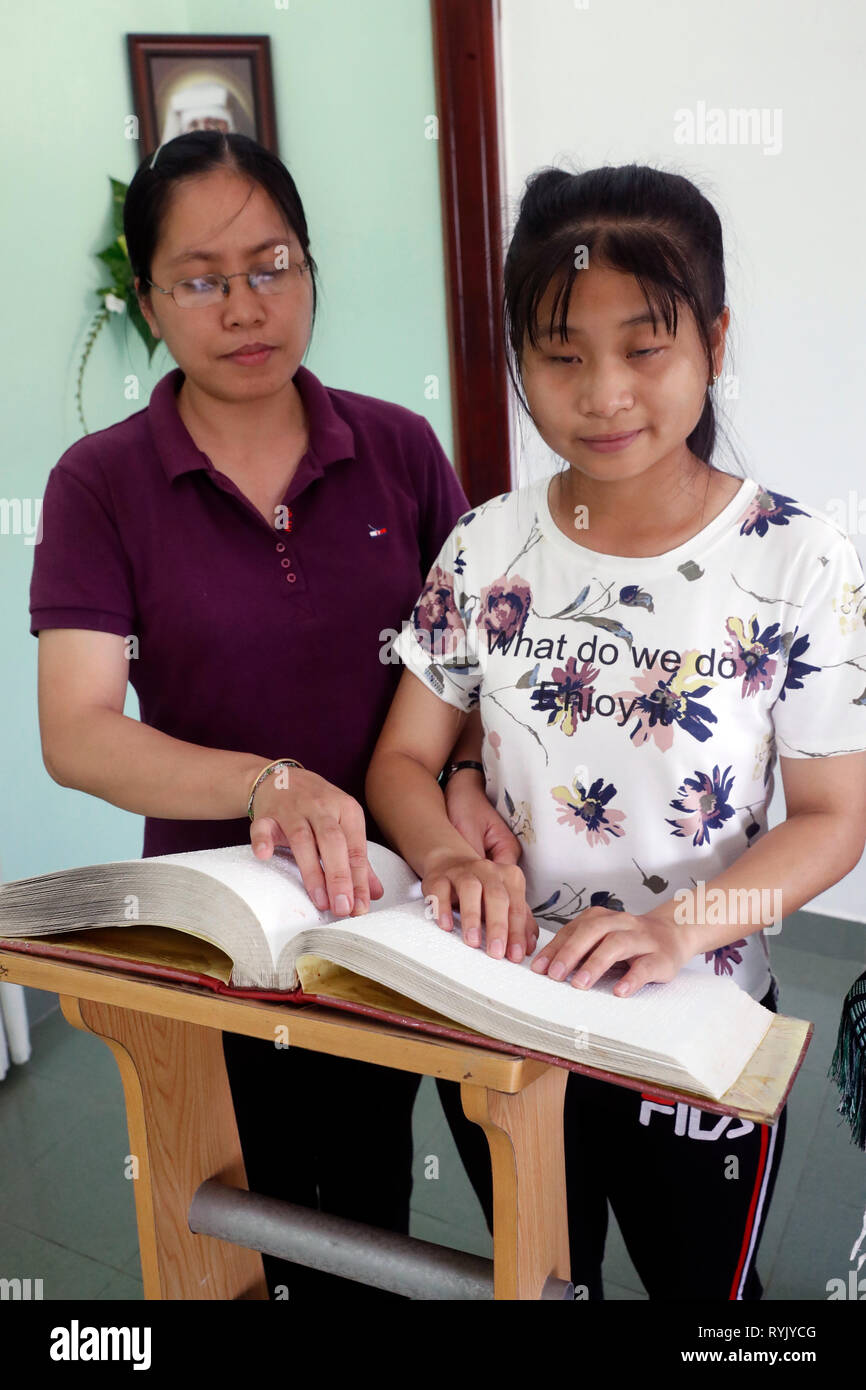 Centro per i bambini ciechi gestito da bambini azione. La cappella cattolica. Ragazza cieca la lettura di una versione braille della Bibbia. Ho Chi Minh city. Il Vietnam. Foto Stock