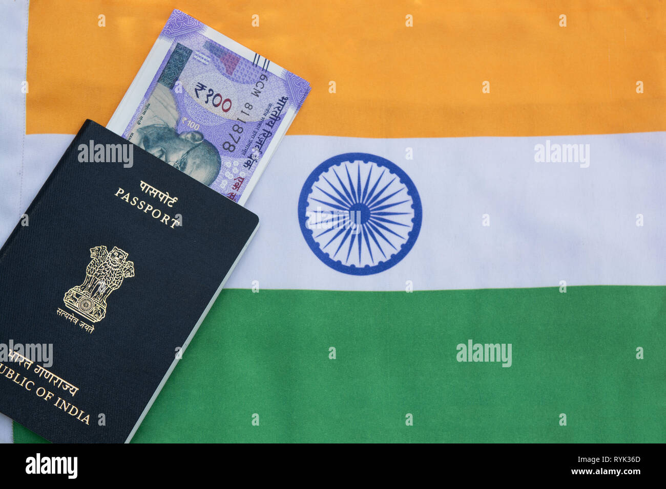 Vista dettagliata del passaporto indiano con la valuta indiana sulla bandiera indiana come sfondo Foto Stock
