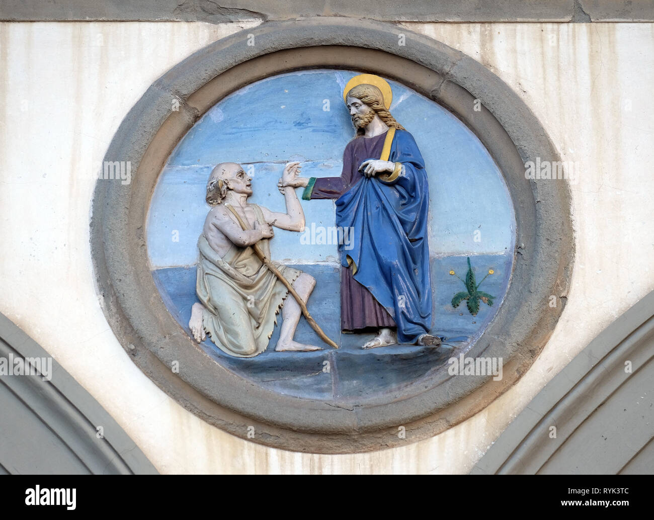 Opere di Misericordia, terracotta invetriata tondo di Andrea della Robbia, situata tra due archi del vecchio Ospedale di San Paolo, a Firenze, Italia Foto Stock