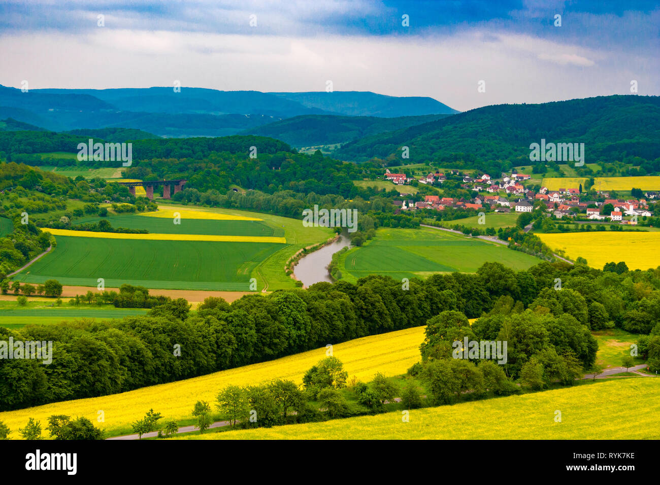 Una fantastica vista del paesaggio della Valle Werra con il fiume Werra, campi coltivati e un ponte ferroviario e la città Oberrieden; circondato da una foresta e... Foto Stock