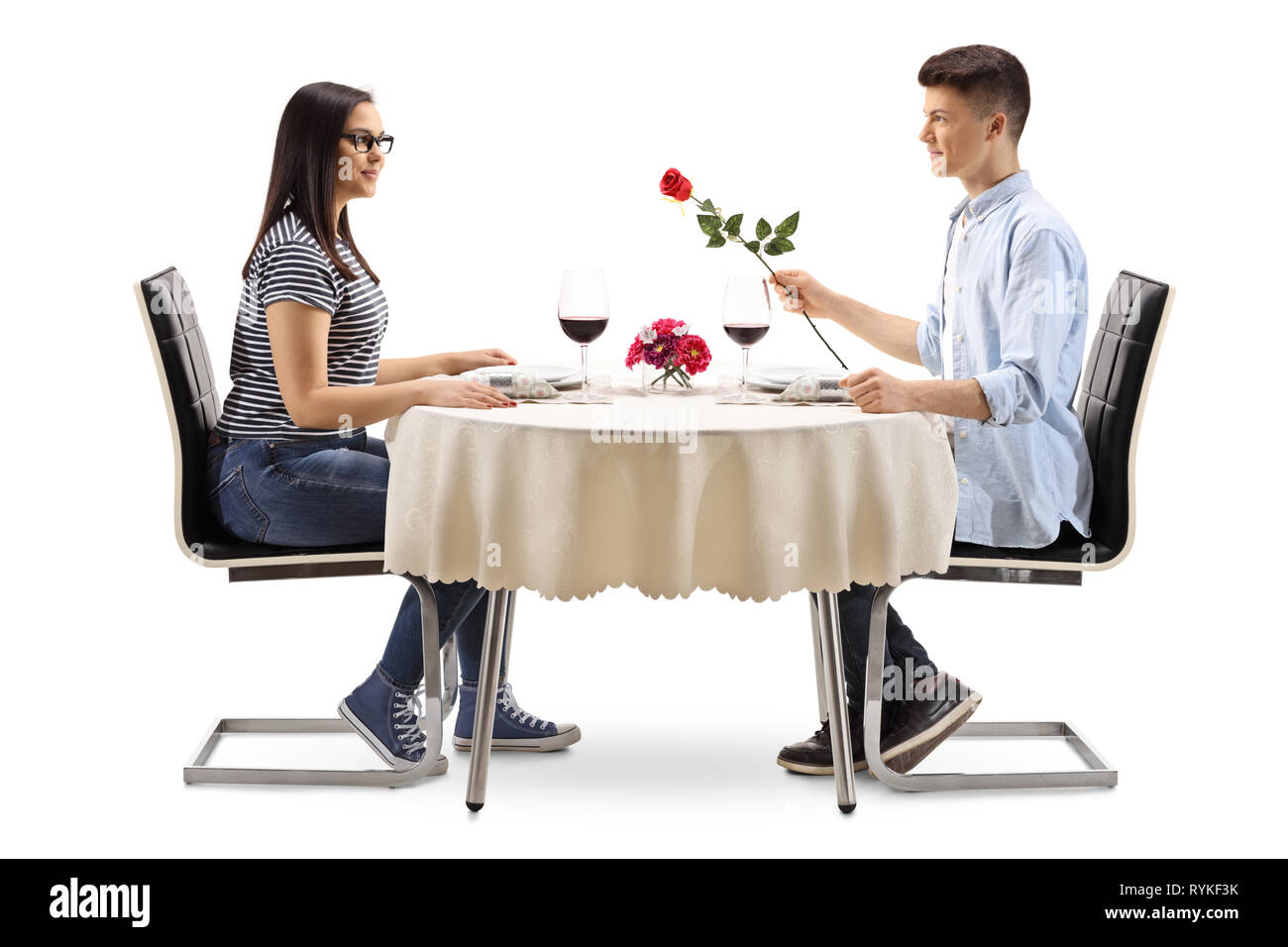 A piena lunghezza profilo di un giovane maschio dando una rosa di una giovane donna in un ristorante tabella isolati su sfondo bianco Foto Stock