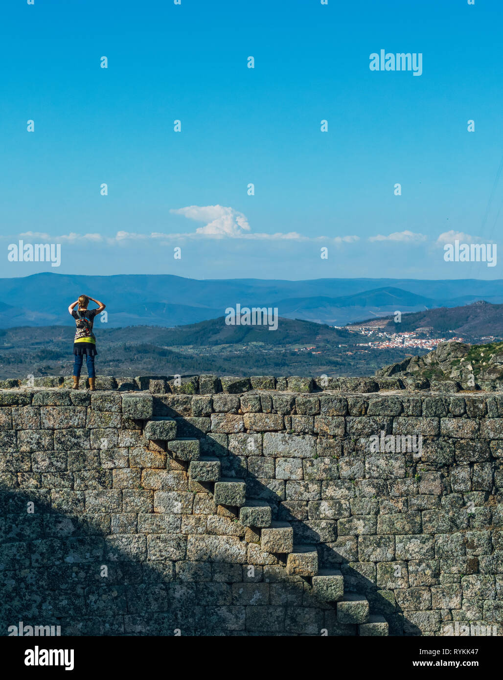 Donna in piedi sulla parte superiore della Monsanto la collina del castello parete. Guardando oltre la vista delle montagne, dei villaggi e delle pianure di Portogallo e Spagna. Foto Stock