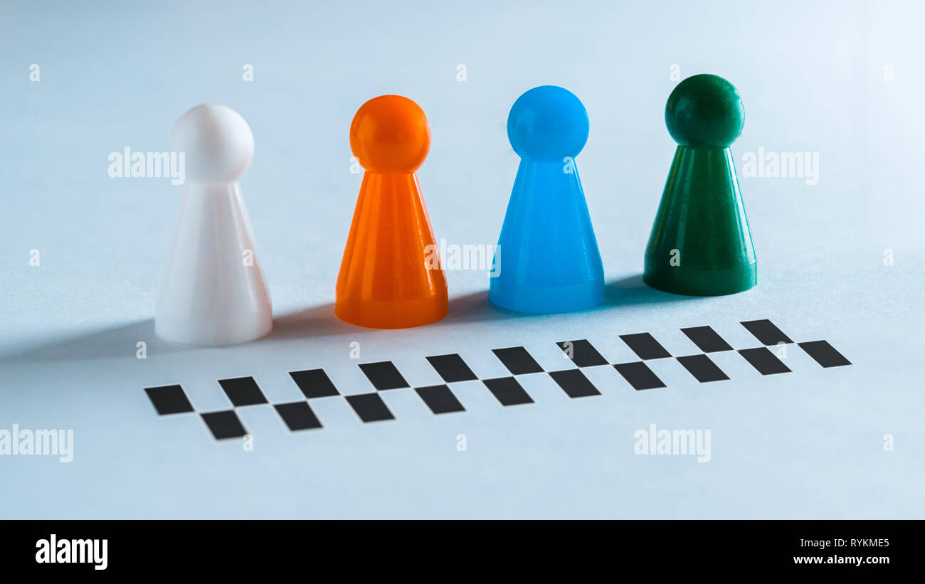 Quattro pezzi colorati per i giochi da tavolo disposti in una fila di fronte all'inizio o fine linea per una gara Foto Stock