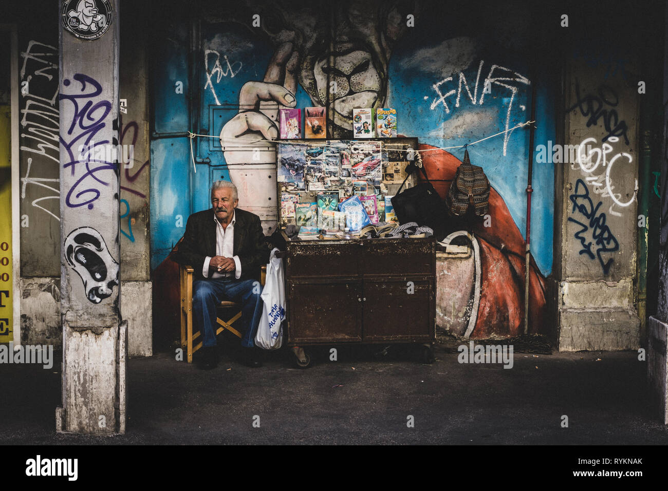 Un anziano uomo italiano vende libri dalla sua Edicola come ha guardato le persone passano in strada. Foto Stock