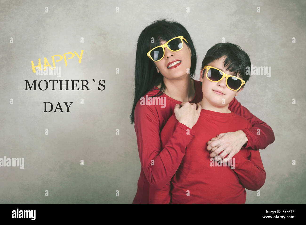 Felice Giornata della madre, madre abbracciando il figlio contro uno sfondo grigio Foto Stock
