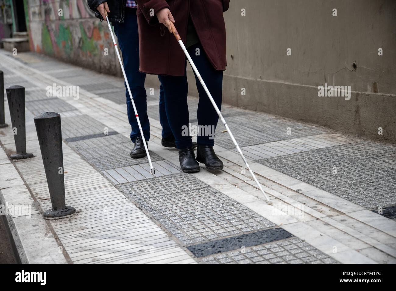 Blind l uomo e la donna che cammina sulla strada utilizzando un bianco bastone da passeggio Foto Stock