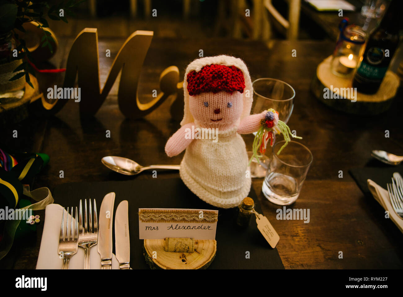Un rustico in legno colazione di nozze tabella impostato con una sposa a crochet doll Foto Stock