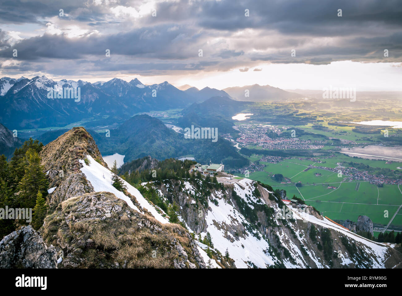 Paesaggio panoramico che si affaccia sulle montagne innevate e nuvole drammatico. I raggi di luce solare che cade su di valle con laghi e piccoli villaggi in Baviera, Germania. Foto Stock