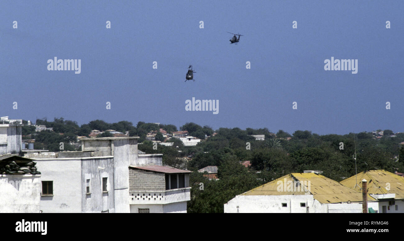 Xx Ottobre 1993 U.S. Esercito Bell AH-1 elicottero Cobra e un OH-58 Kiowa osservazione Scout elicottero di pattuglia di basso sopra i tetti di Mogadiscio, Somalia. Foto Stock