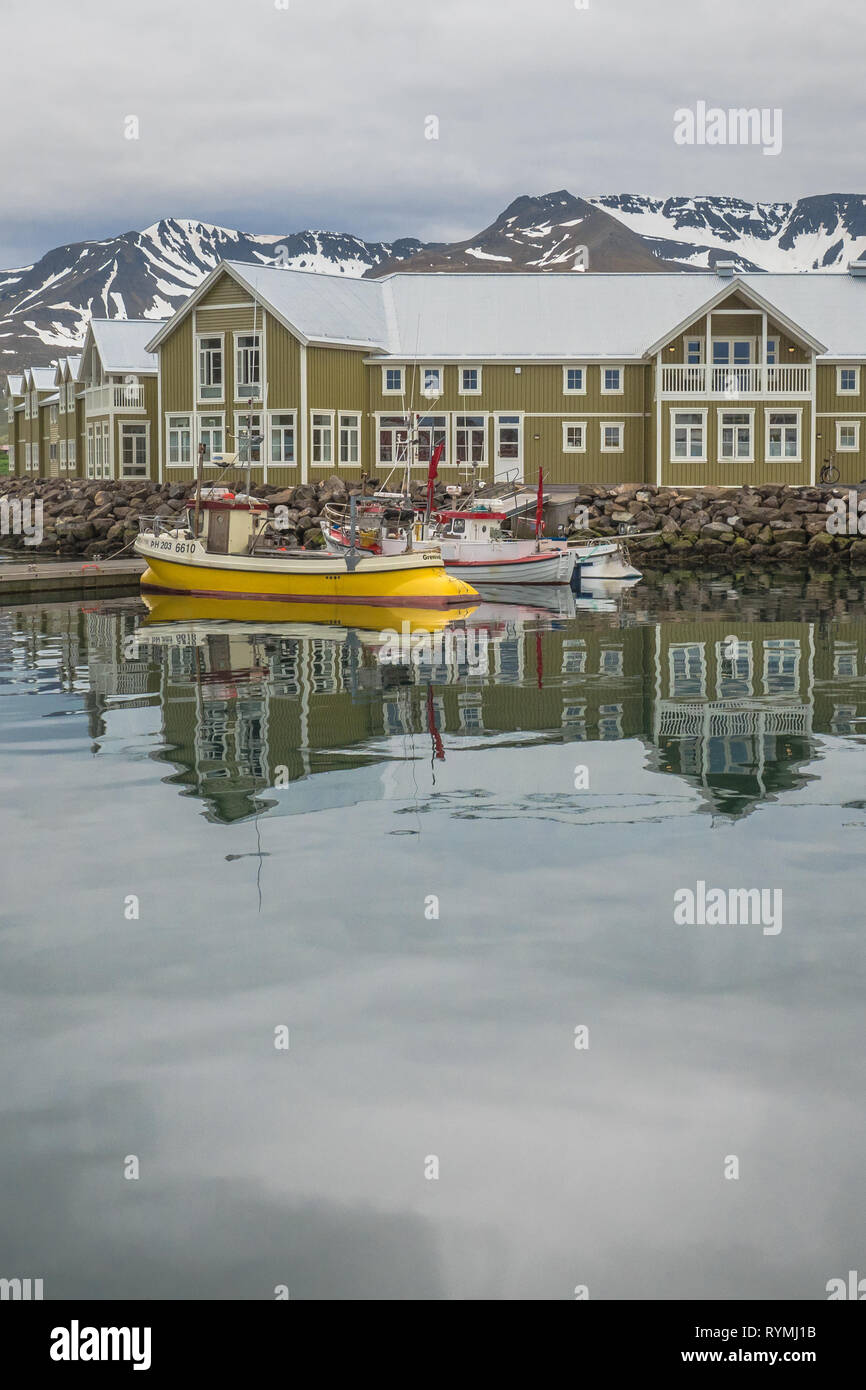 Giallo e Bianco barche da pesca presso il dock al di fuori del verde e bianco Siglo Hotel sul porto in Siglufjörður (Siglufjörður Affitto) Islanda Foto Stock