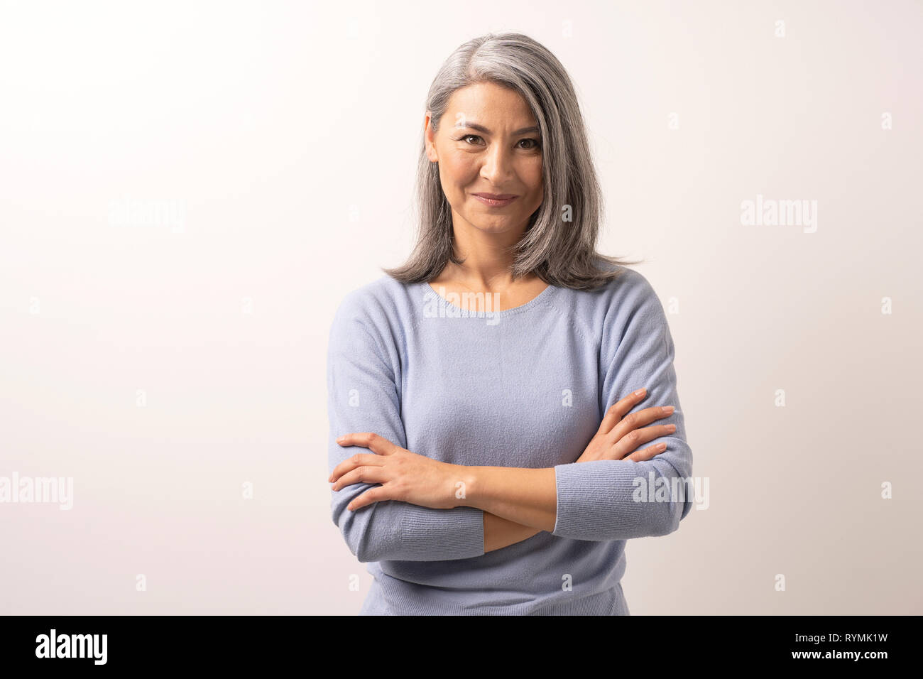 Bella grey-haired donna con bracci incrociati Foto Stock