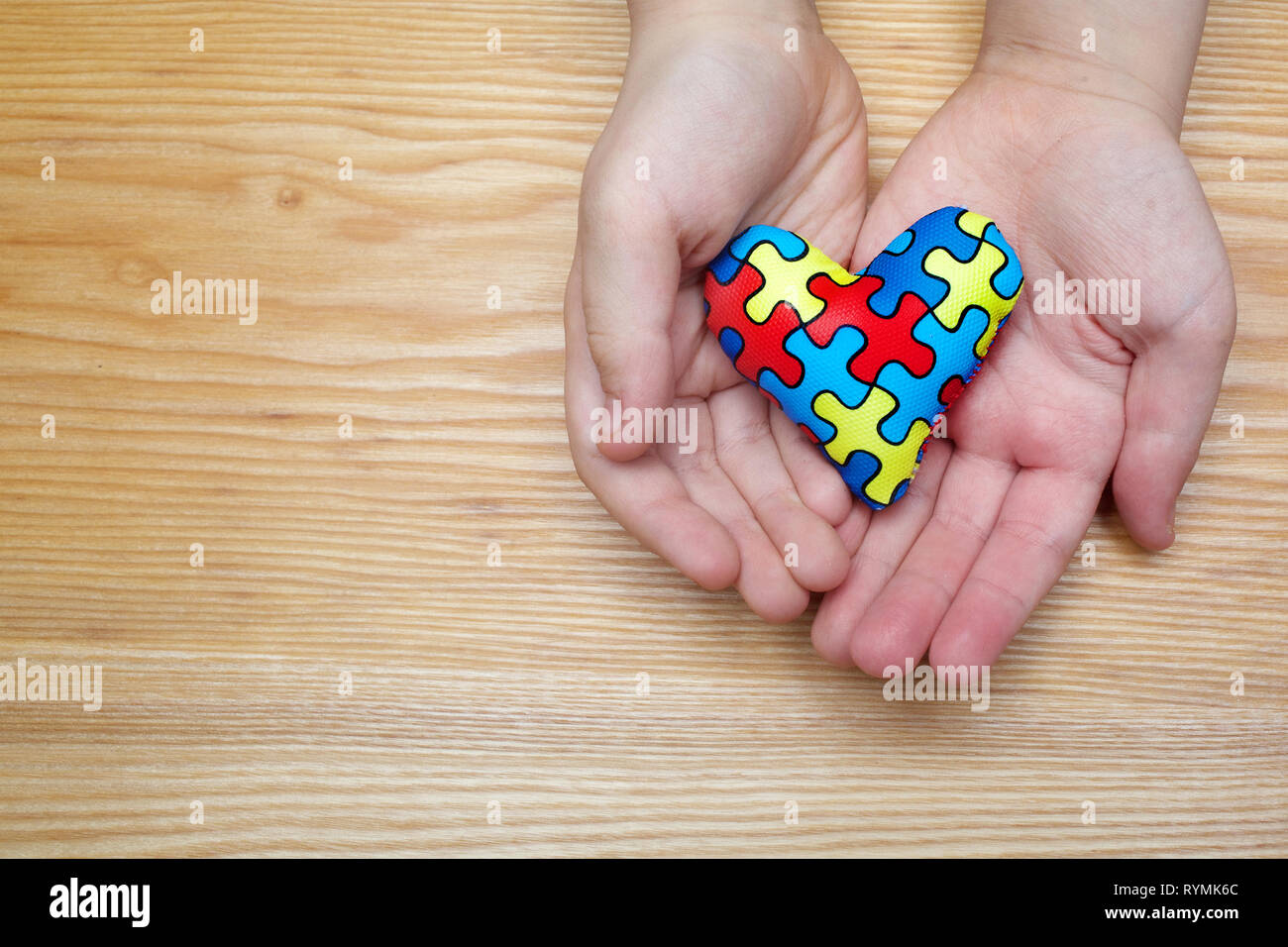 Mondo autismo giornata di sensibilizzazione, puzzle o jigsaw pattern sul cuore con il bambino autistico le mani Foto Stock