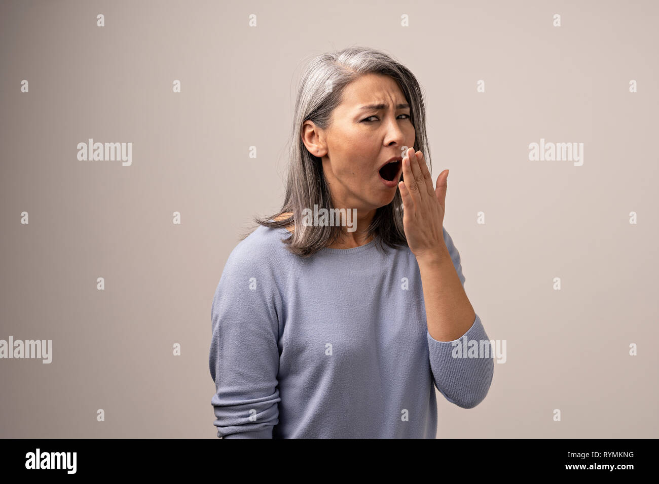 Stanco donna asiatica sbadigli in photo studio Foto Stock