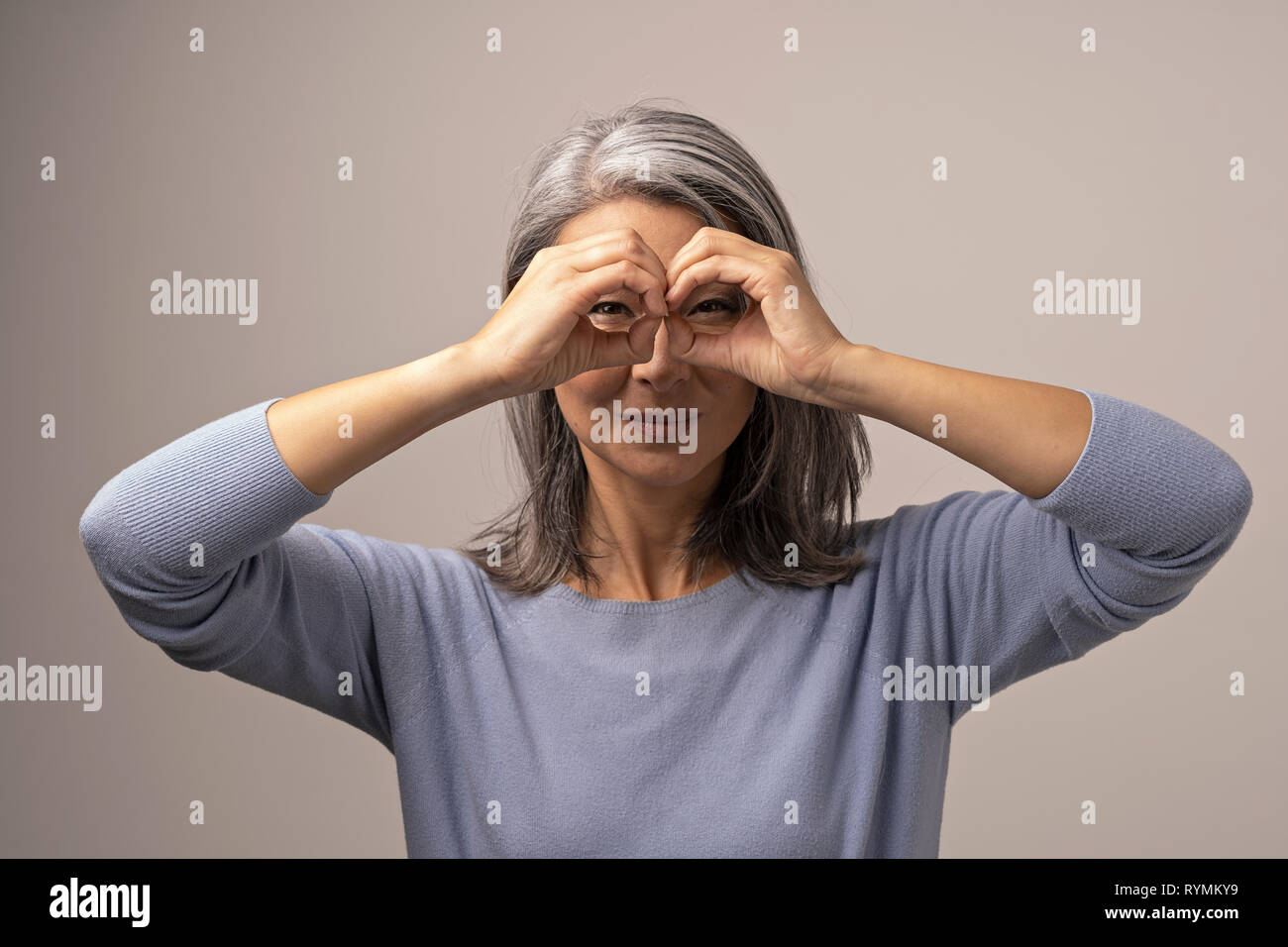 Asian donna matura non ok gesto come un binocolo. Foto Stock