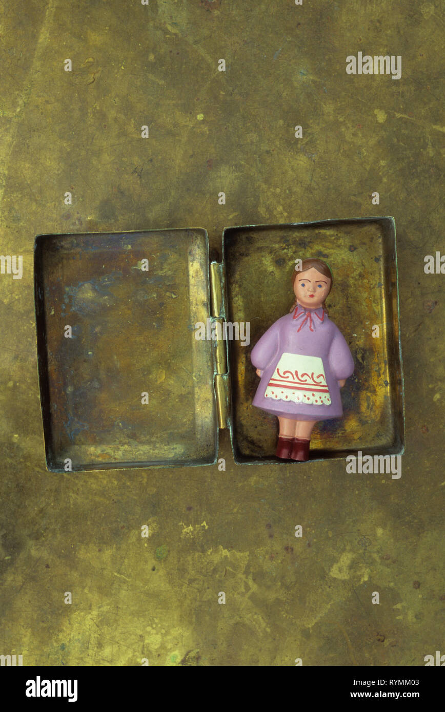 Miniatura di legno verniciato bambola in abito russo giacente in opacizzato scatola di ottone Foto Stock