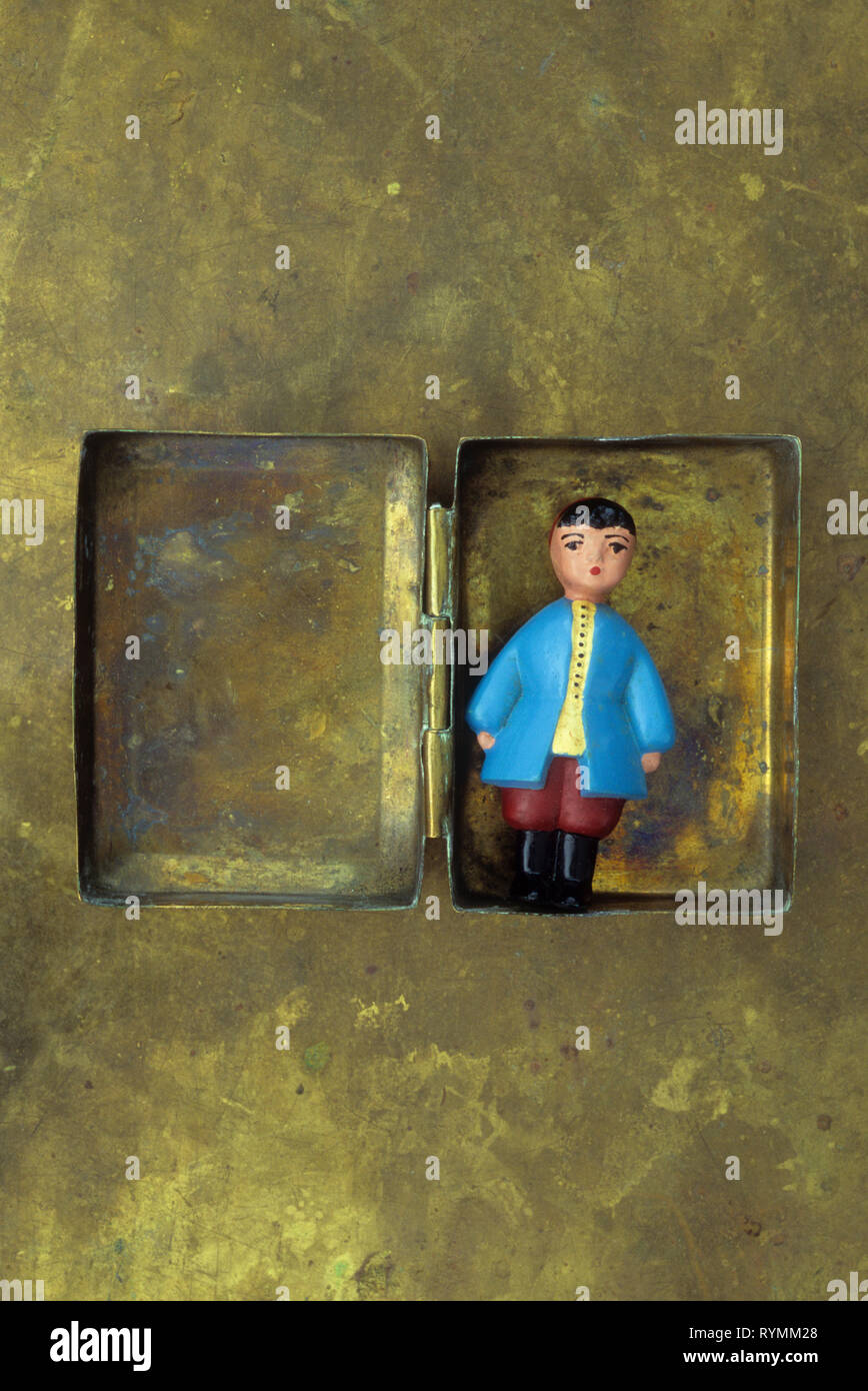 Miniatura di legno verniciato bambola in abito russo giacente in opacizzato scatola di ottone Foto Stock