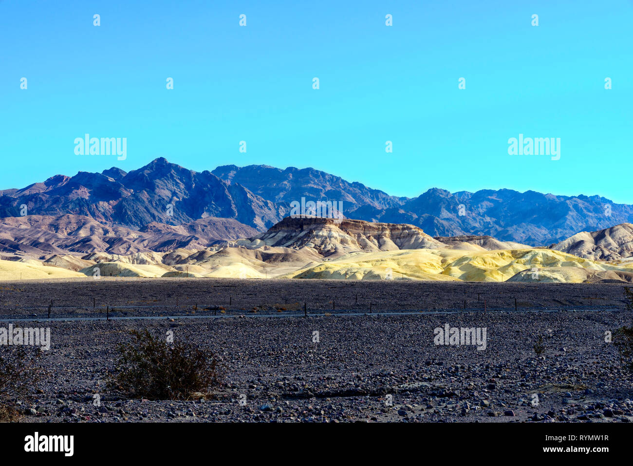 Aride montagne del deserto con il bianco delle colline e desolata valle con vegetazione rada sotto il luminoso cielo blu. Foto Stock